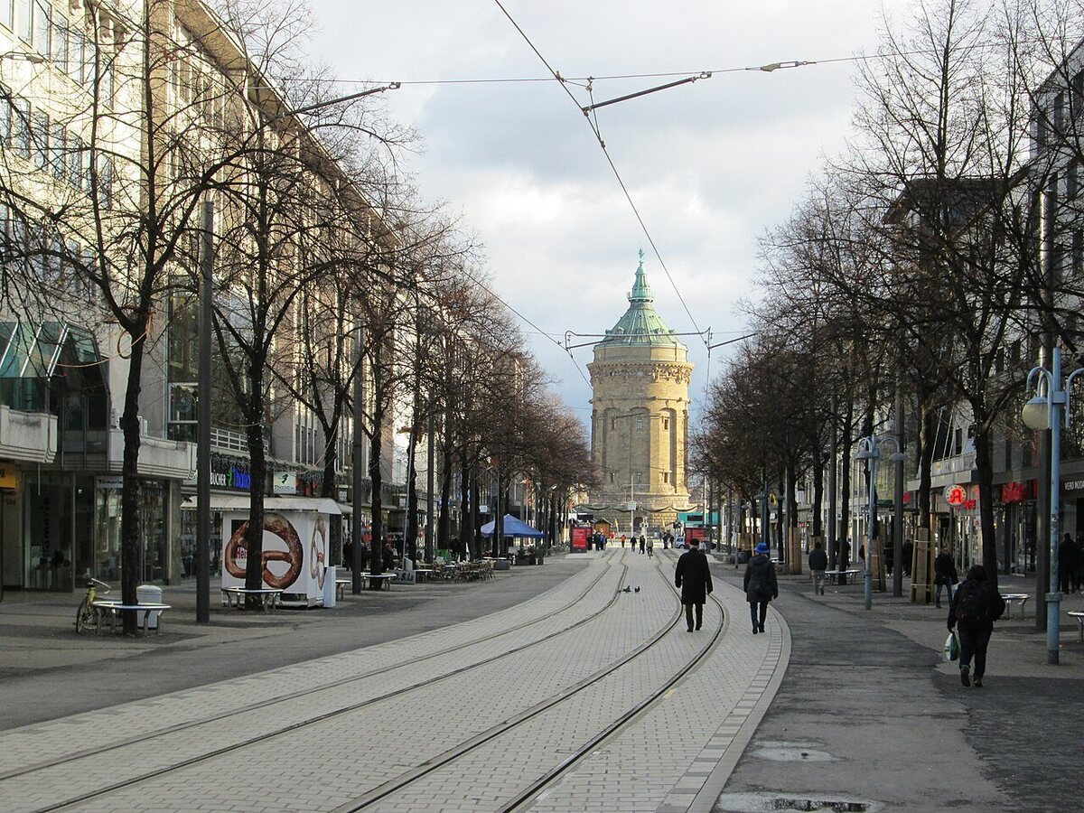 Die Planken: breite Einkaufsstraße mit Straßenbahngleisen und Baumreihen, am Ende der Wasserturm